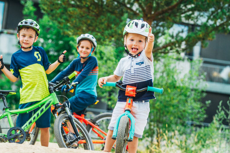 three happy kids giving thumbs up while on a bike ride